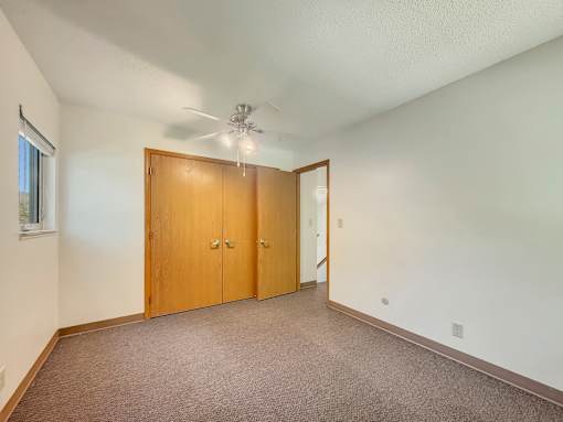 A room with a ceiling fan and a brown door.