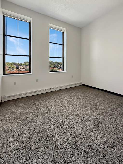 A room with two windows and carpeted floor.