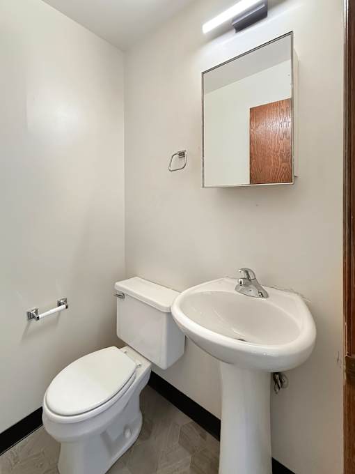 A white toilet and sink in a small bathroom.
