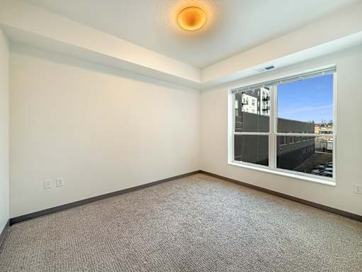 A room with a window and a carpeted floor.