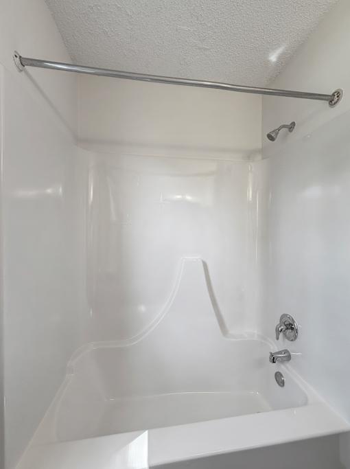 A white bathroom with a white tub and a white shower curtain.
