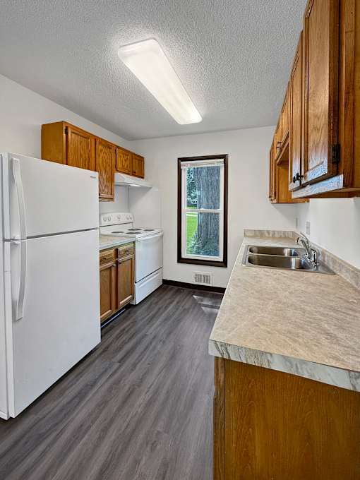 A kitchen with a white refrigerator and wooden cabinets.