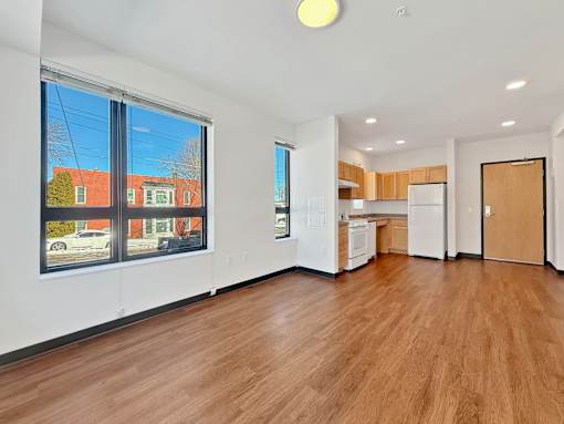 A spacious living room at Stryker Senior Apartments in West St. Paul with wooden floors and white walls.