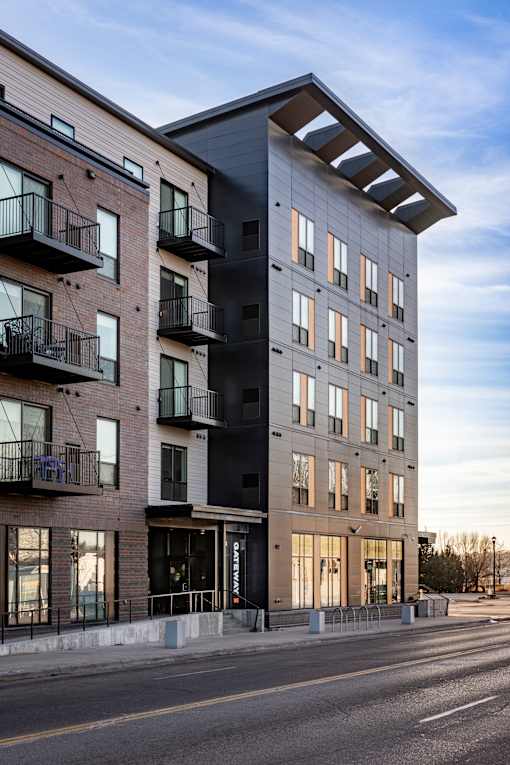 A modern apartment building with balconies on the second floor.