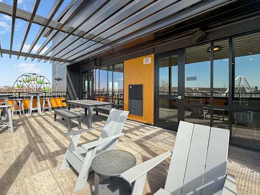 A patio with chairs and tables is covered by a roof.
