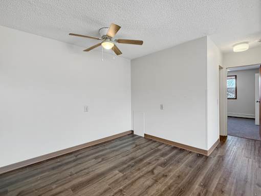 A room with a ceiling fan and wooden flooring.