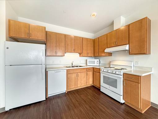 A kitchen at The Lumin in the Highland Park neighborhood of St Paul with wooden cabinets and white appliances.