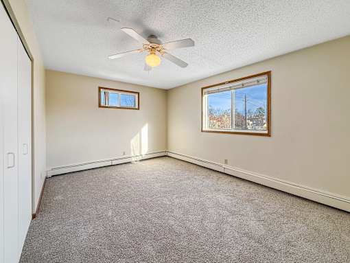 A room with a ceiling fan and two windows.