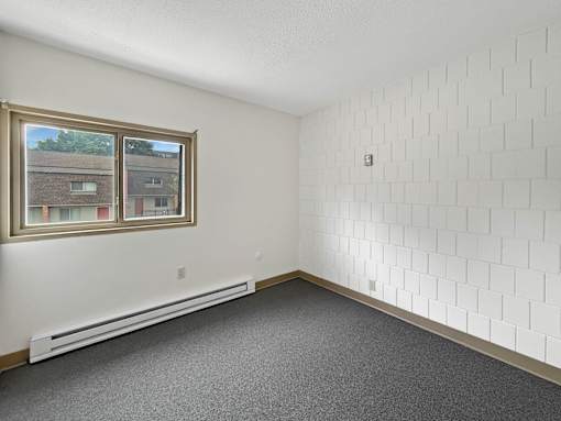 A photo of an apartment bedroom at Liberty Plaza with a window and carpeted floor