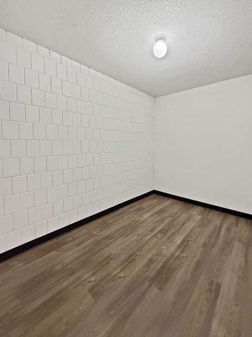 A room with wooden flooring and white tiled walls.