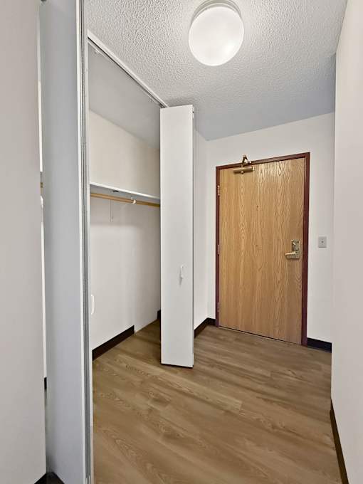 A hallway with a wooden door and a white wall.