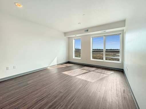 A room with wooden flooring and a large window overlooking a field.