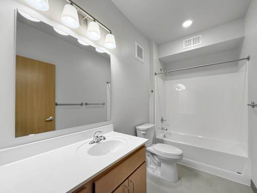 A bathroom with vanity, toilet, shower and tub