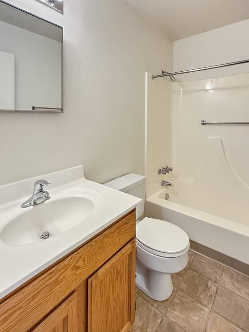 A white sink with a silver faucet is on a countertop next to a white toilet.