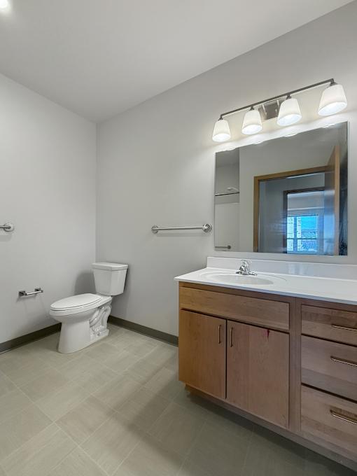 A bathroom with vanity,  a light bar and a toilet