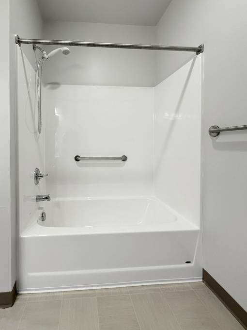 A white bathtub with a shower curtain rod above it.