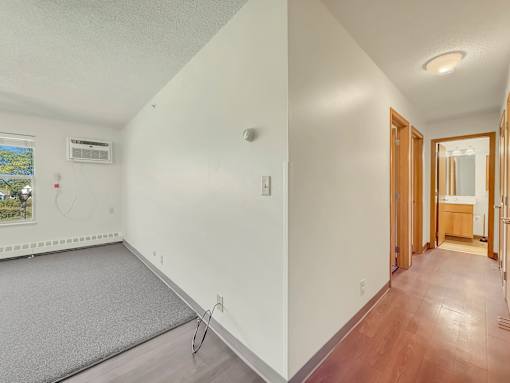 A room with a grey carpet and wooden flooring.