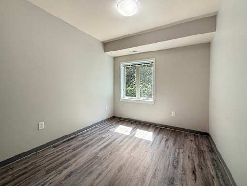 A room with wooden flooring and a window.