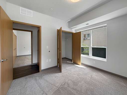 A room with a carpeted floor and a window with blinds.
