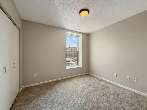 A room with a carpeted floor and a window showing a cityscape outside.