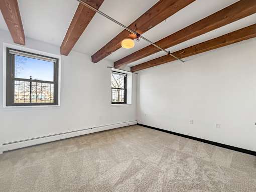 A room with a window and a carpeted floor.