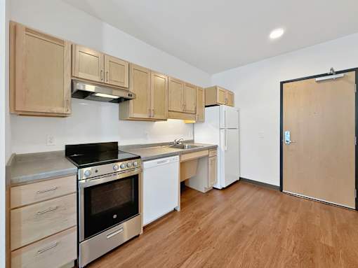A studio apartment kitchen at Stryker Senior Apartments in West St. Paul with wooden cabinets and stainless steel appliances.