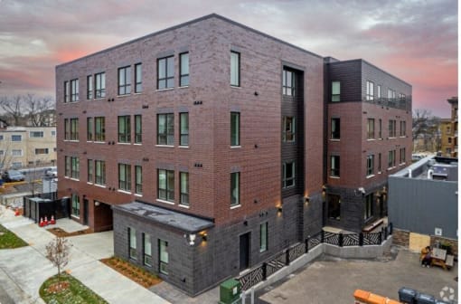 a brick apartment building with a sunset in the background