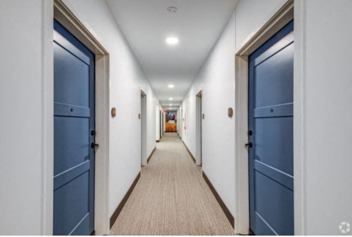 a long hallway with blue doors and white walls