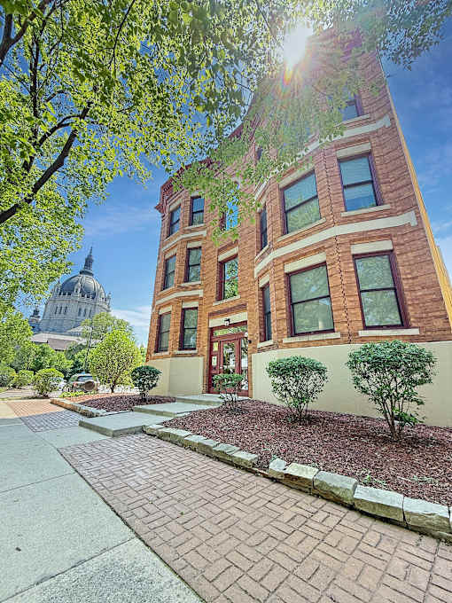 A building with a brick facade and a dome in the background.