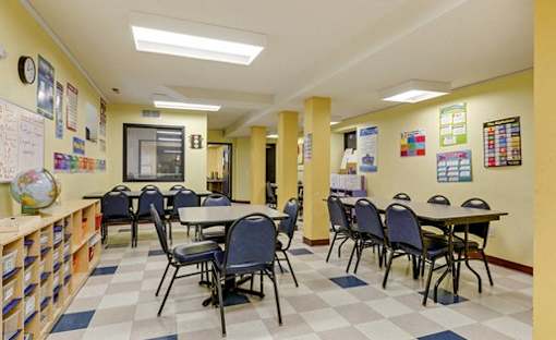 A classroom with tables and chairs, a globe, and educational posters on the walls.