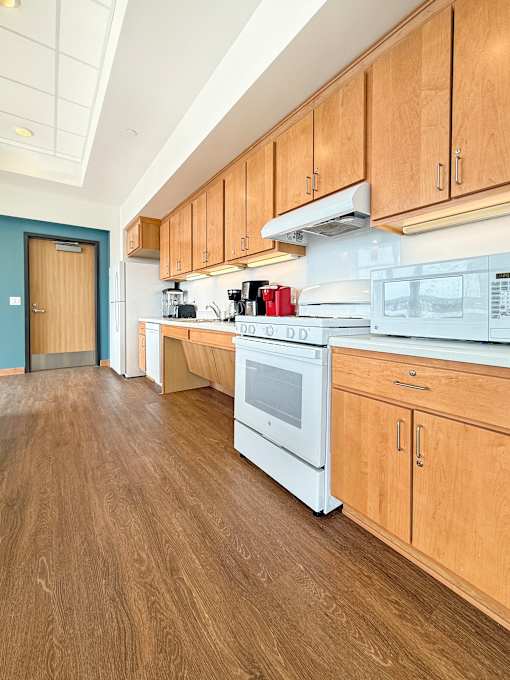 The Community Room  kitchen with wooden cabinets and a white oven.