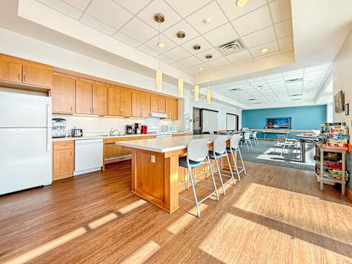 The community room at The Lumin in the Highland Park neighborhood of St Paul with wooden floors and a white refrigerator.