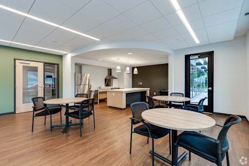 The Community Room at Stryker Senior Apartments in West St Paul with tables and chairs and a kitchen