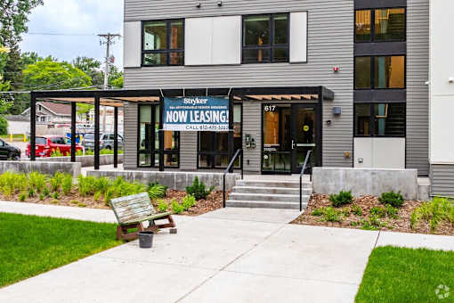 the front of the now leasing banner for Section 8 Vouchers at Stryker Senior Apartments in West St. Paul with a sidewalk and a bench