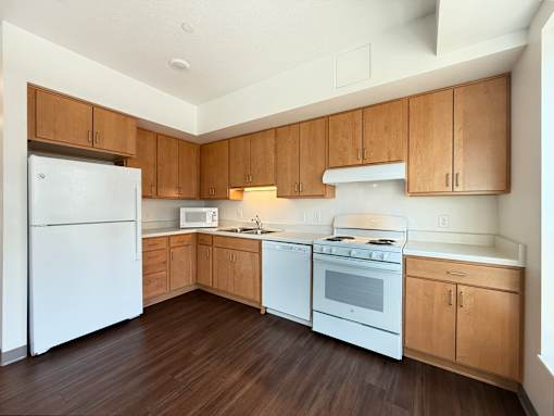 A kitchen with white appliances and wooden cabinets.