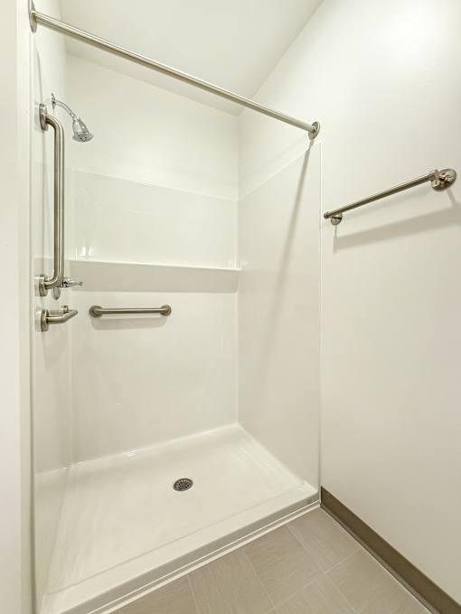 A white shower stall with a glass door and a silver handle.