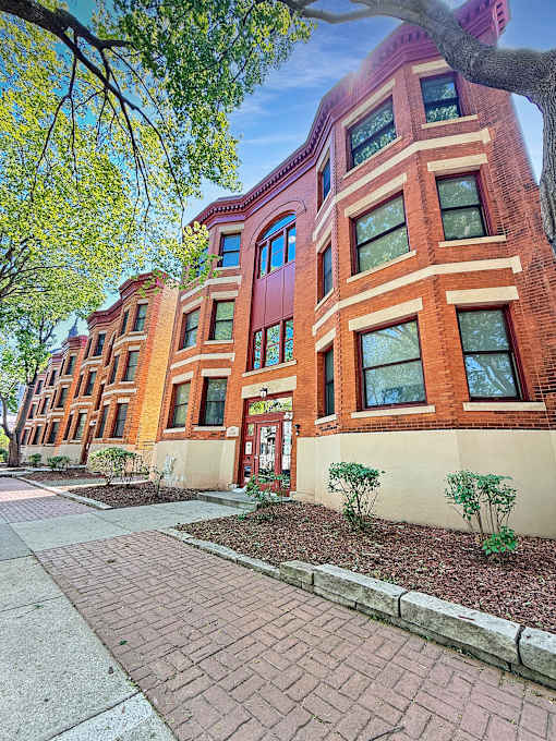 A red brick building with a tree in front.