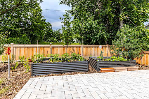 the garden has three large planters in front of a wooden fence