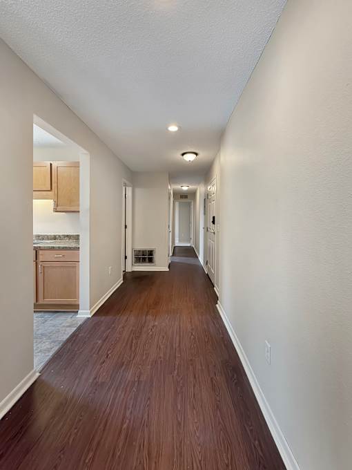 A long hallway with wood floors and white walls.
