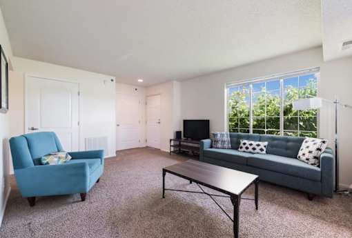 A living room with a blue couch, a blue chair, and a black table.