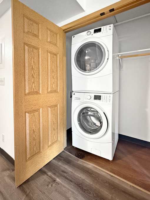 A white washing machine is in front of a wooden door.