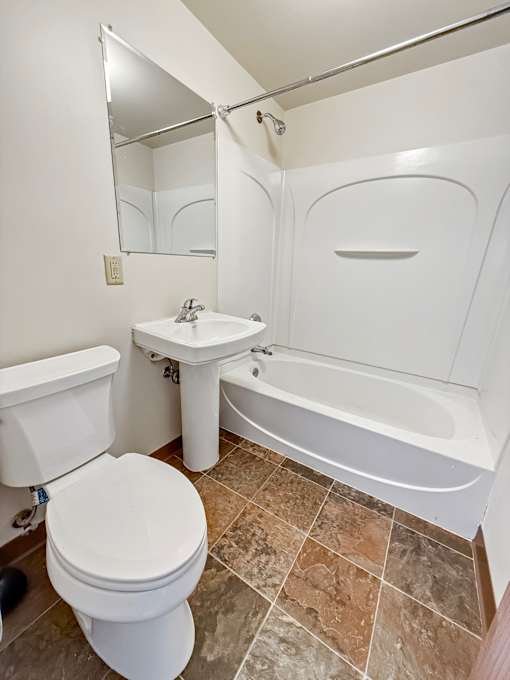 A white toilet sits next to a sink in a small bathroom.