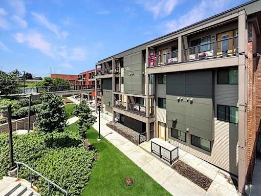 A modern apartment complex with a green lawn in front.