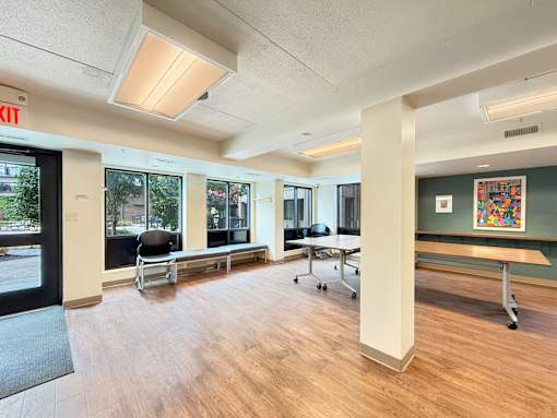 A room with a wooden floor, a white column, and a black chair.
