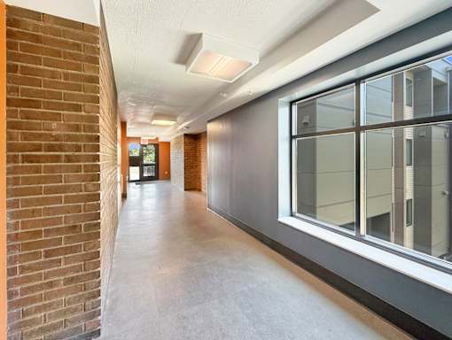 A long hallway with brick walls and windows on the side.