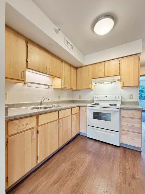 A kitchen with wooden cabinets and a white stove top oven.