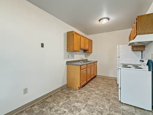 A kitchen with white appliances and wooden cabinets.