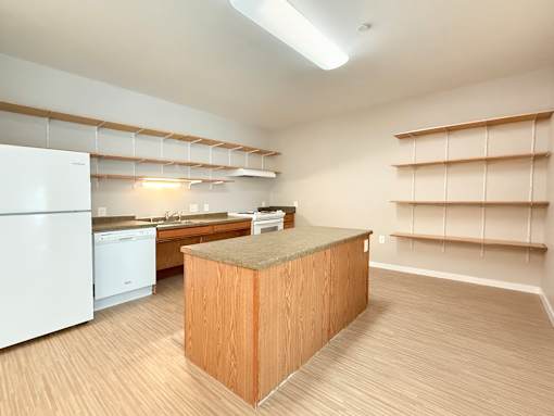 A kitchen with a white refrigerator and a wooden island.