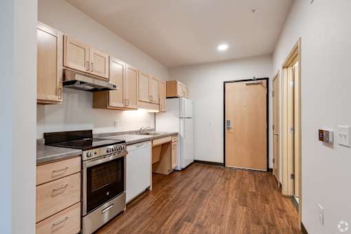 a Stryker Senior Apartments in West St. Paulk itchen with wood floors and white appliances and a door to a hallway
