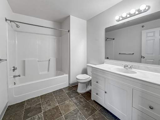 A white bathroom with a tiled floor and a large mirror.